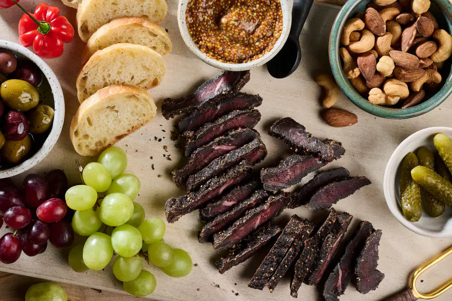 Joburg Steak Slices on a board with bread, olives and nuts