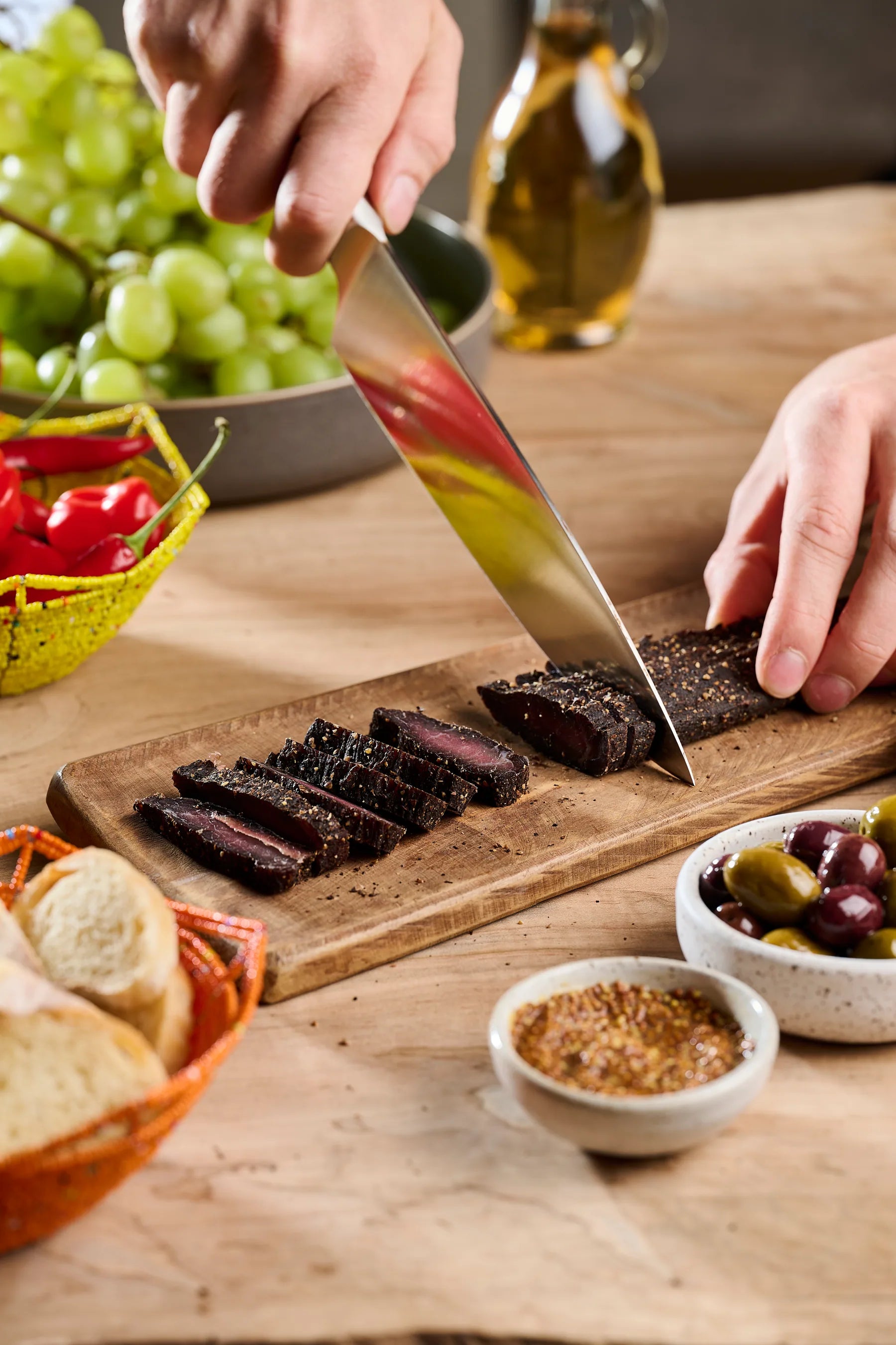 Whole-muscle air-dried steak being sliced on a wooden board